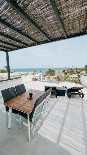 uma mesa de madeira e cadeiras num pátio com praia em WAKE UP BY THE SEA FLATS em Protaras
