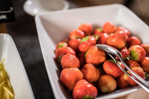 a white bowl of strawberries with spoons in it at Hotel Bergfrieden in Martello