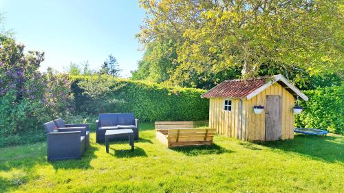 a backyard with a bench and a wooden shed at Quiet and cozy apartment close to nature in villa. in Tilst