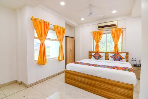 a bedroom with a large bed with orange curtains at FabHotel Grand Hazra Inn in Kolkata