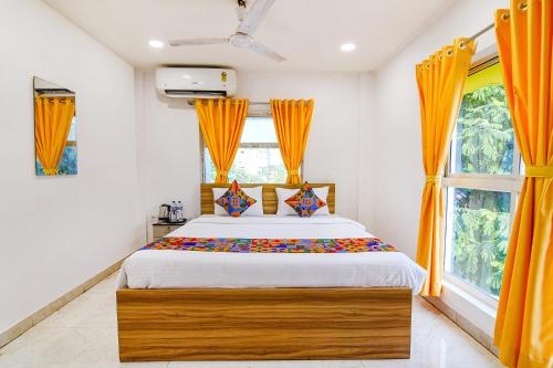 a bedroom with a large bed with orange curtains at FabHotel Grand Hazra Inn - Nr Ballygunge Station in Kolkata