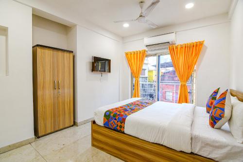 a bedroom with a bed and a window at FabHotel Grand Hazra Inn - Nr Ballygunge Station in Kolkata