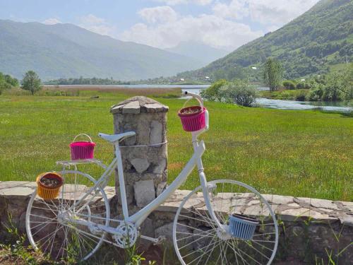 a white bike with two baskets sitting on a stone wall at Plav Lake Camping in Plav