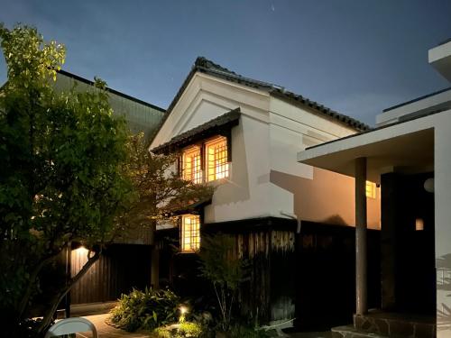 a white house with its lights on at 源泉かけ流しの一棟貸し温泉宿The Bath & Bed Dogo in Matsuyama