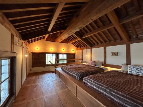 松山的住宿－The Bath & Bed Dogo 築110年の蔵をリノベーションした源泉掛け流しのお宿，大客房设有两张带木制天花板的床。