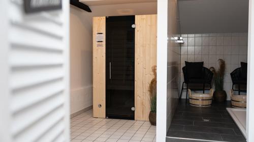 two pictures of a bathroom with a door and a chair at Parkhotel Cloppenburg in Cloppenburg