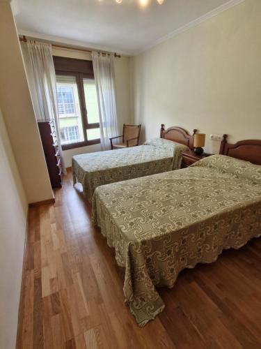 a hotel room with two beds and a window at Apartamento playa Carrabuxeira (Sanxenxo) in Sanxenxo