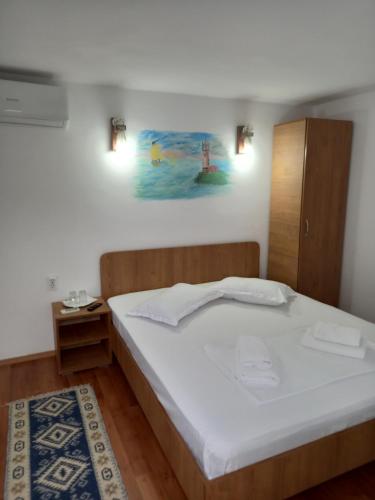 een slaapkamer met een wit bed en een schilderij aan de muur bij Casa Tulceanu in Sulina