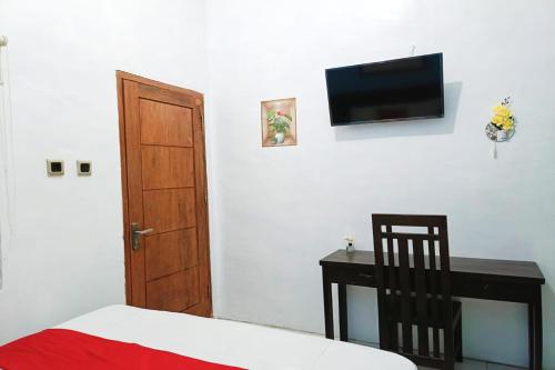 a bedroom with a bed and a desk and a flat screen tv at OYO 93837 Ipeda Family Residence in Banyuwangi