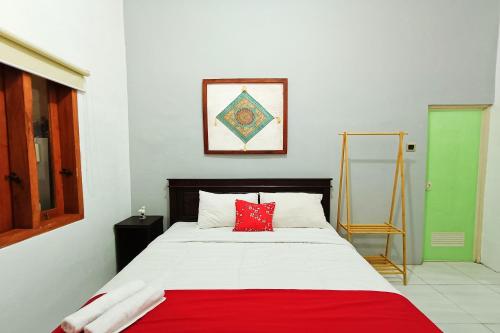 a bedroom with a bed with a red pillow on it at OYO 93837 Ipeda Family Residence in Banyuwangi