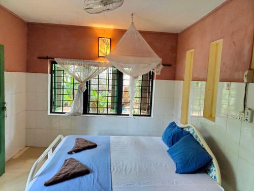 a bedroom with a bed with blue pillows and a window at Jungle House Kep in Kep