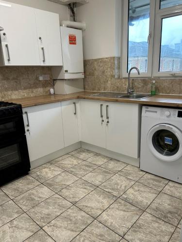 a kitchen with white cabinets and a washing machine at London City Inn Stepney in London