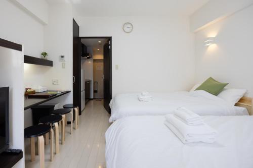 a bedroom with two beds and a kitchen with a counter at 錦系町天空樹景觀飯店 Skytree View Kinshicho in Tokyo