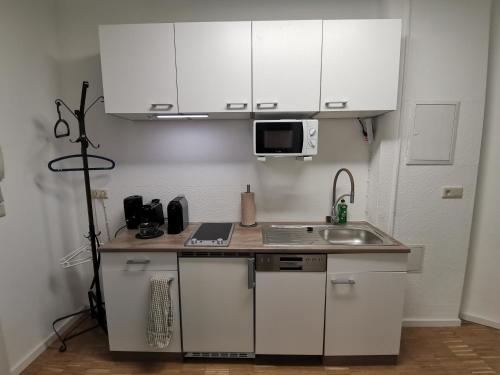 uma pequena cozinha com armários brancos e um lavatório em Have a nice home em Leipzig