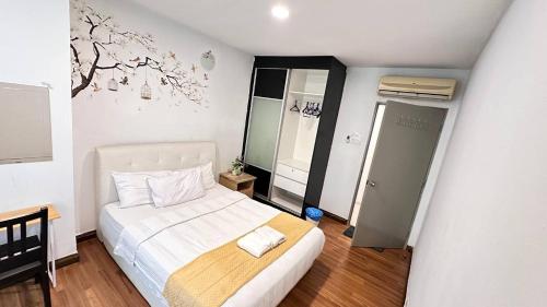 een slaapkamer met een wit bed en een muurschildering van bomen aan de muur bij Taragon Apartment - KL in Kuala Lumpur