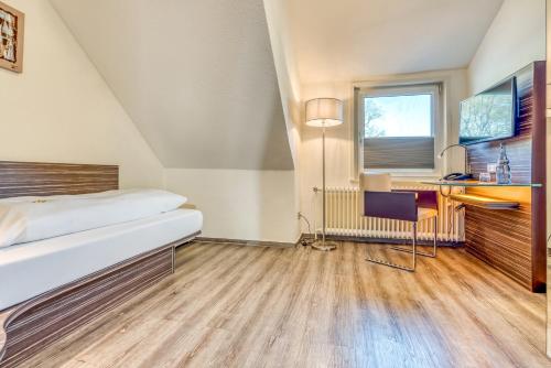 a bedroom with a bed and a desk and a window at Ringhotel Forellenhof in Walsrode