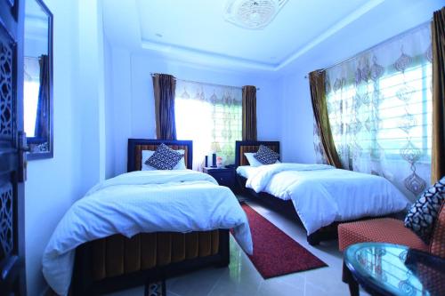 a bedroom with two beds and a window at Candle Wood in Bhurban