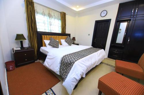 a bedroom with a bed and a chair and a clock at Candle Wood in Bhurban