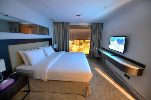a hotel room with a large bed and a tv at Carlton Tower Hotel Kuwait in Kuwait