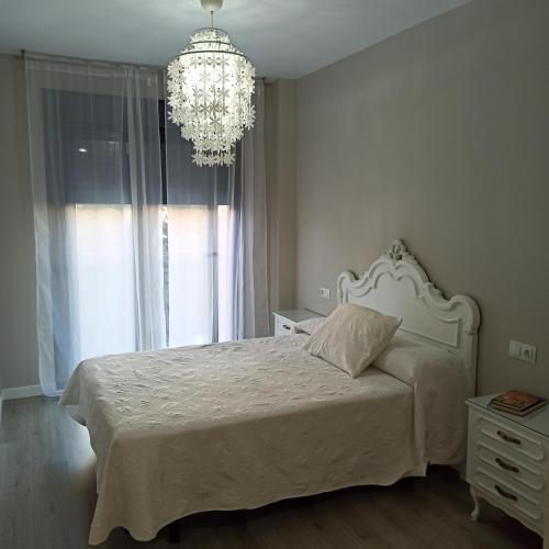 1 dormitorio con cama blanca y lámpara de araña en Apartamento MyR, en Benajarafe
