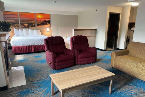 a hotel room with two chairs and a bed at Days Inn & Suites by Wyndham Des Moines Airport in Des Moines
