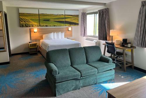 デモインにあるDays Inn & Suites by Wyndham Des Moines Airportのベッドとソファ付きのホテルルーム