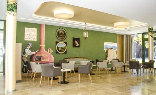un restaurante con paredes verdes, mesas y sillas en Hofgut Farny en Kißlegg