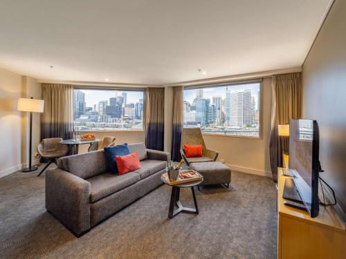 a living room with a couch and a tv at Novotel Sydney Darling Harbour in Sydney