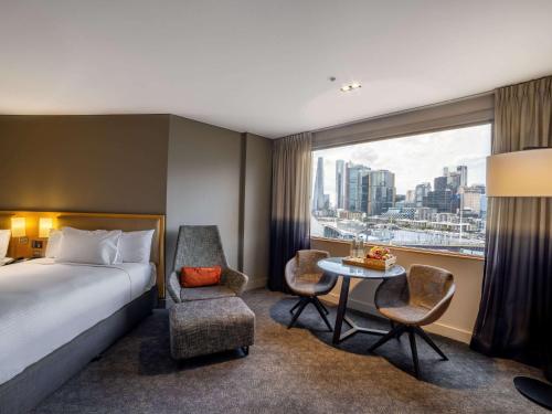 a hotel room with a bed and a table and a window at Novotel Sydney Darling Harbour in Sydney