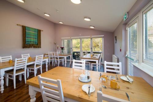 a dining room with wooden tables and white chairs at Godshill Park Barn in Ventnor