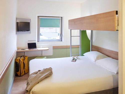 a bedroom with a bed and a desk with a laptop at ibis budget Birmingham International Airport – NEC in Bickenhill