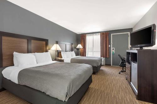 a hotel room with two beds and a flat screen tv at Quality Inn Gainesville in Gainesville