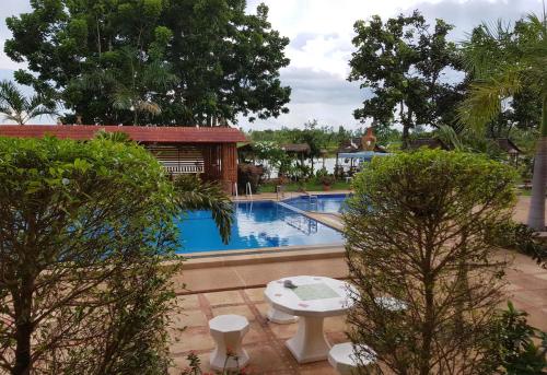 a swimming pool with a table and trees in front at Changthai Comfort Guest House in Ban Nong Phai