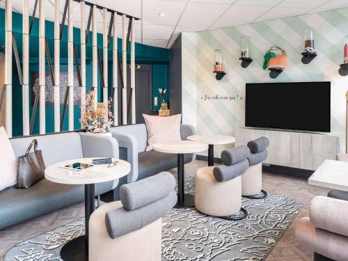 eine Lobby mit Tischen und Stühlen und einem Flachbild-TV in der Unterkunft ibis Styles Sceaux Paris Sud in Sceaux