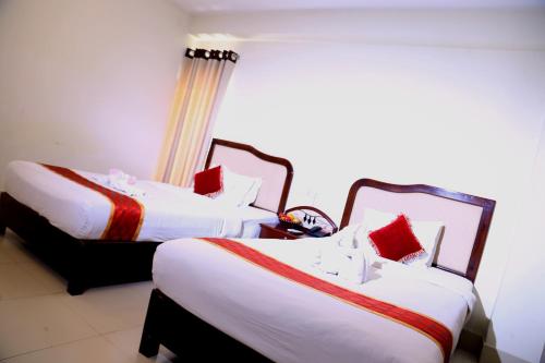two beds in a hotel room with red pillows at Panshi Inn Sylhet in Sylhet