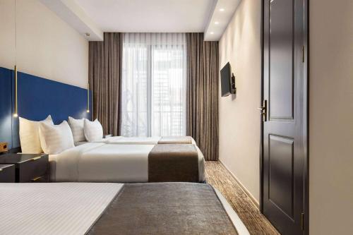 a hotel room with two beds and a window at Ramada by Wyndham Tbilisi Old City in Tbilisi City