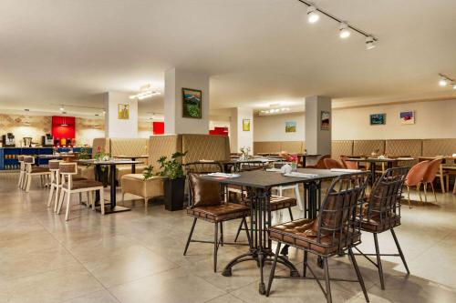 a dining room with tables and chairs in a restaurant at Ramada by Wyndham Tbilisi Old City in Tbilisi City