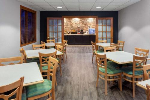 a dining room with tables and chairs and a kitchen at Links Bos Landen Hotel & Spa of Pella, Trademark by Wyndham in Pella