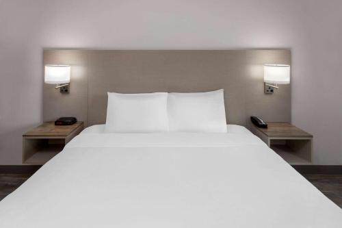 a bedroom with a large white bed with two tables at Links Bos Landen Hotel & Spa of Pella, Trademark by Wyndham in Pella