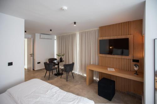 a hotel room with a bed and a desk with a television at Griffin Suites in Heraklio Town