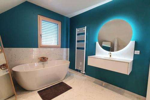 une salle de bain avec une grande baignoire et un miroir dans l'établissement Modern House 3 rooms/Jacuzzi pool/quiet near Basel, à Helfrantzkirch