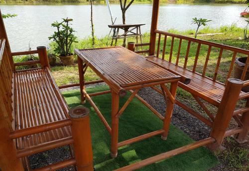 a wooden table and two chairs sitting next to a lake at Changthai Comfort Guest House in Ban Nong Phai