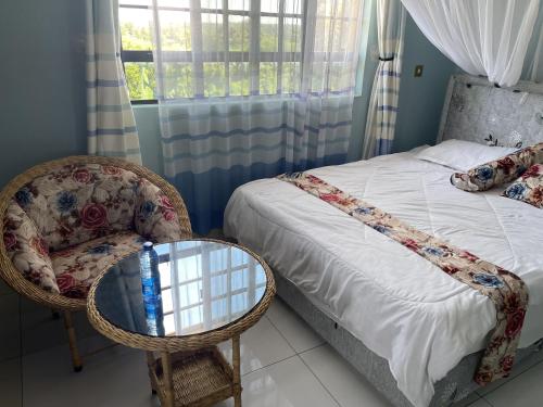 VILLA ESPERANZA KITUI في Kitui: غرفة نوم بسرير وكرسي وطاولة