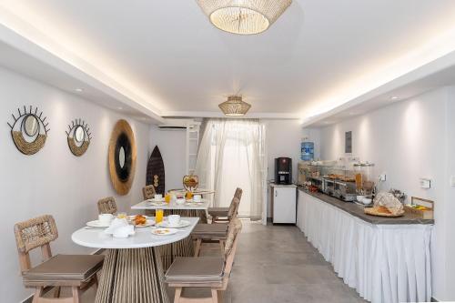 a dining room with tables and chairs and a kitchen at Hotel Villa Flora in Naxos Chora