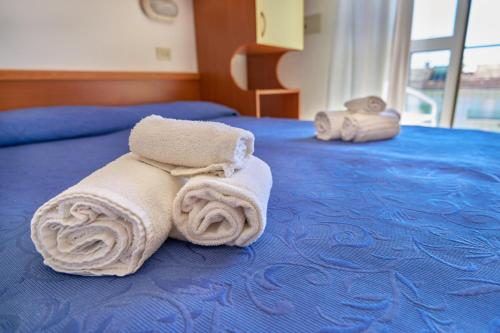 una pila de toallas sentadas encima de una cama en Nuovo hotel ANTHISA en Lido di Savio