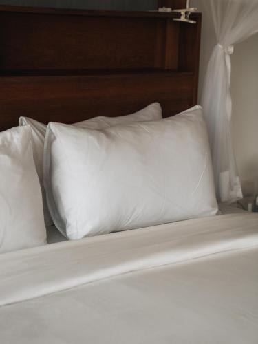 a bed with white pillows on top of it at The Nine Mirissa in Mirissa