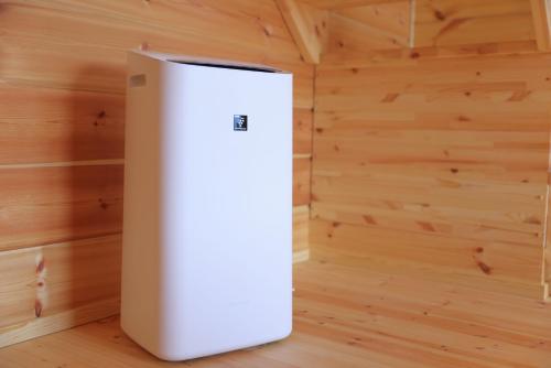 a white refrigerator in a room with wooden walls at 果樹園グランピングヴィラHARASAWA in Minakami