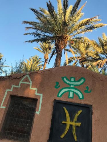 a sign on the side of a building with palm trees at Bivouac Lot Of Stars in Ouarzazate