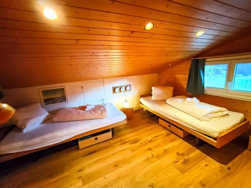 two beds in a room with wooden walls and wooden floors at Apartment Bodmi on the top in Grindelwald