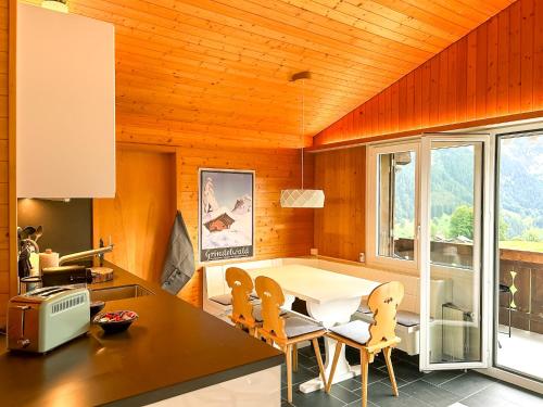 a kitchen with a dining room table and chairs at Bodmi on the top Apartment - Aare Jungfrau AG in Grindelwald